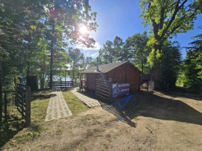 Działka rekreacyjna z domkiem i linią brzegową jeziora.
